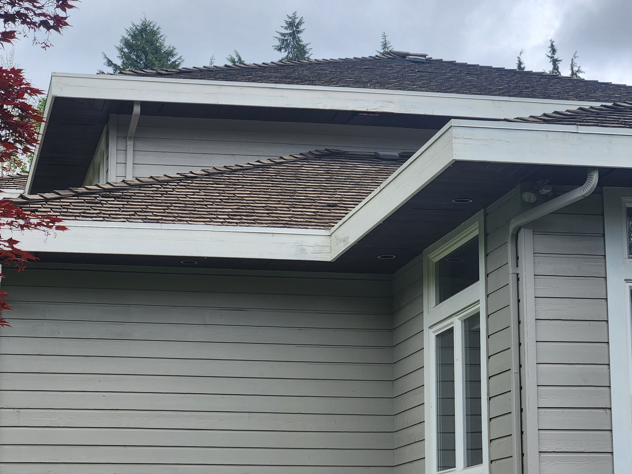 A weathered brown cedar shake roof on a home, aged and greyed before restoration.